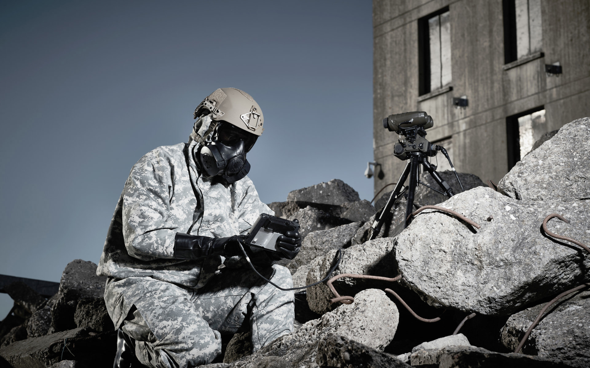 A soldier kneeing on rubble wearing a helmet and respirator